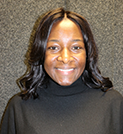 Black woman wearing a black turtle neck and a grey background