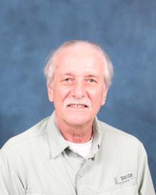 Older white man with white hair and mustache wearing a white undershirt and light green button up shirt.